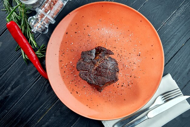 Appetitlich gegrilltes gereiftes Ribeye-Rindsteak, serviert in einem Teller auf Holztisch