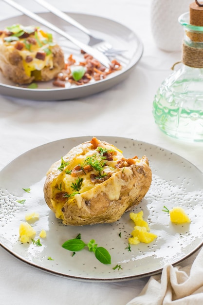 Appetitliche, doppelt gebackene Kartoffeln in ihrer Haut mit Käse- und Speckkrümeln auf Tellern auf einem Holztisch Flexitarian Diet Nahaufnahme Vertikale Ansicht