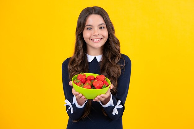 Appetitliche Erdbeere Porträt eines süßen Teenager-Mädchens, das Erdbeeren isoalted auf gelbem Hintergrund isst