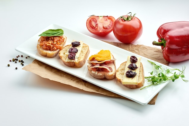 Appetitliche italienische Antipasti - verschiedene Bruschetta mit Lachs, Käse und Jamon, serviert auf einem weißen Teller auf einem weißen Teller
