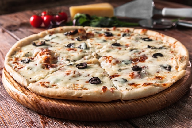 Appetitliche Pizza auf rustikalem Holztisch mit Zutaten. Traditionelles italienisches Essen, Menüfoto.
