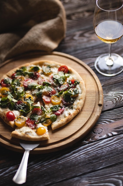 Appetitliche Pizza mit Tomaten und Käse auf dunklem Holzhintergrund.