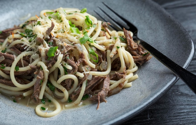 Appetitliche Spaghetti mit Fleisch und Kräutern auf einem Teller auf einem Tisch in einem Restaurant Nahaufnahme