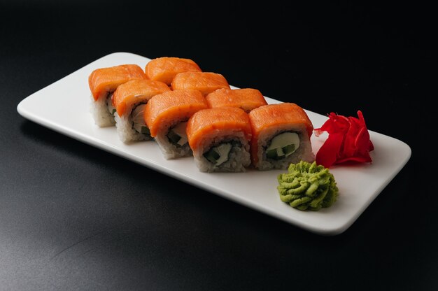appetitliche Sushi-Rolle Philadelphia mit Käsegurke und Lachs auf schwarzem Hintergrund
