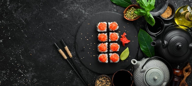 Appetitliche Sushi-Rollen mit Fisch und Kaviar auf einer schwarzen Steinplatte Draufsicht der japanischen Küche