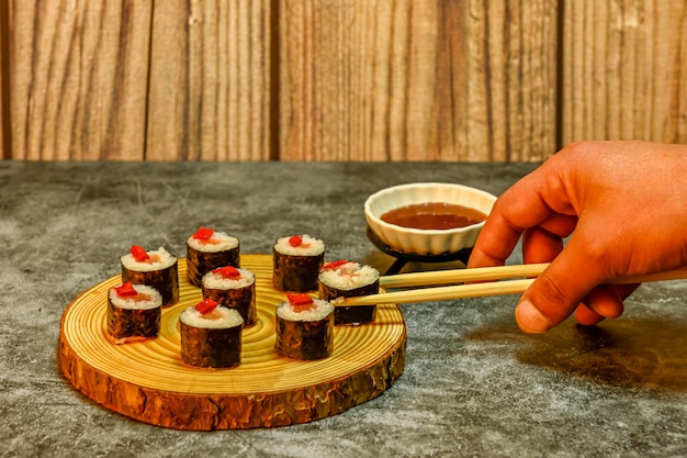 Appetitliche Sushi-Rollen mit Lachsreis und Paprika auf einer Holzplatte