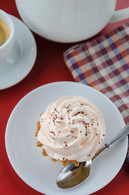 Appetitlicher Kuchen mit rosa Sahne auf einem roten Tisch