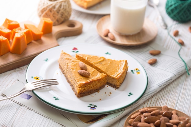 Appetitlicher Kürbis-Käsekuchen und Glas Milch, Mandeln