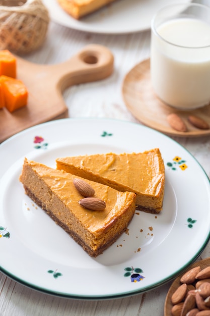 Appetitlicher Kürbis-Käsekuchen und Glas Milch, Mandeln