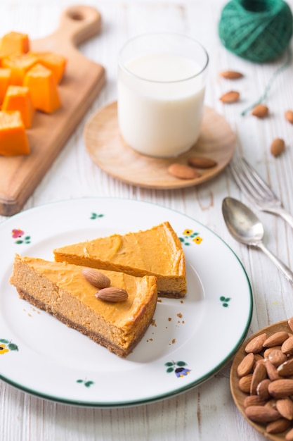 Appetitlicher Kürbis-Käsekuchen und Glas Milch, Mandeln