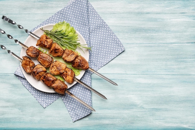 Foto appetitlicher schaschlik auf einem teller mit salat und rosmarin auf blauem holzhintergrund draufsicht