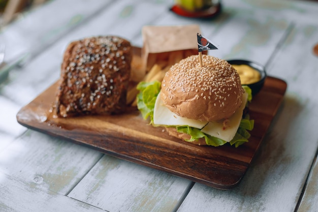 Appetitliches Fast-Food-Mittagessen auf einem Holzständer mit Pommes Frites und Soße. Nahansicht.