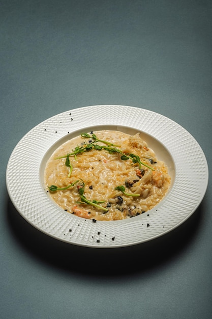 Appetitliches Pilzrisotto, garniert mit mikrogrünen Gänsekeimen in einem schönen weißen Teller. Italienische Küche, einfaches, köstliches Restaurant serviert