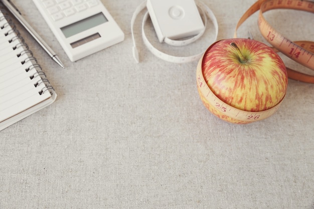 Apple, cinta métrica, cuaderno y fondo de la calculadora para el plan de dieta, plan de pérdida de peso