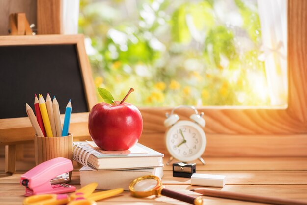 Apple colocada en un libro con equipo educativo junto a la ventana a la luz de la mañana, concepto de regreso a la escuela y espacio de copia