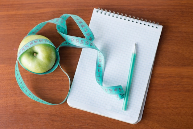 Apple e um caderno em um fundo de madeira. saúde