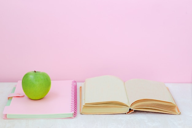 Apple, livro, caderno sobre a mesa no fundo rosa