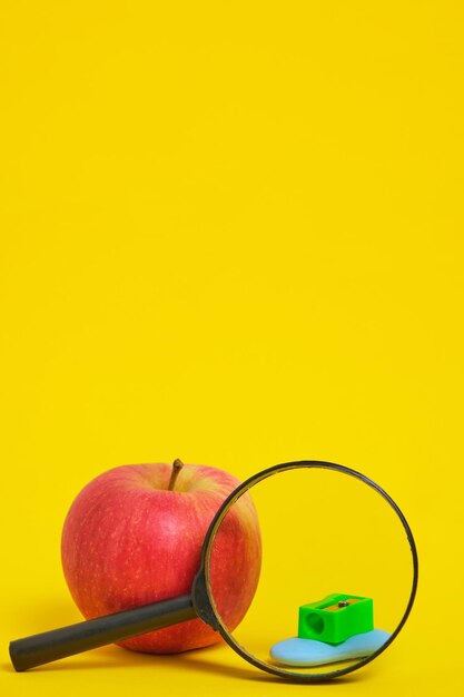 Apple lupa y sacapuntas con fondo amarillo borradorPreparación para la escuela