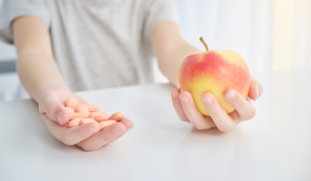 Apple y pastillas en las manos. Concepto de vitaminas naturales.