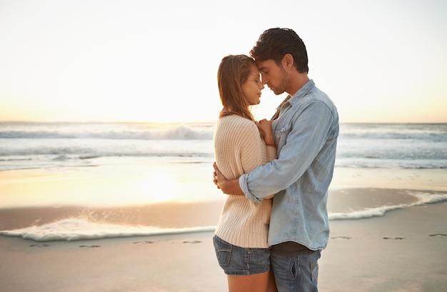 Apreciando este momento Um jovem casal feliz celebrando seu amor ao pôr do sol no ser