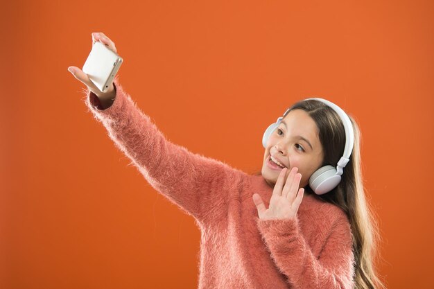 Aprecie o conceito de música Melhores aplicativos de música que merecem ouvir Ouça gratuitamente Aplicativo móvel para adolescentes Menina ouça música fones de ouvido modernos e smartphone tirando selfie Obtenha assinatura de música