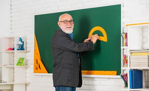 Foto aprenda geometria torne-se facilmente bom em matemática tronco na sala de aula professor sênior use ferramenta no quadro-negro tutor barbudo em óculos de volta à escola transferidor régua física e matemática