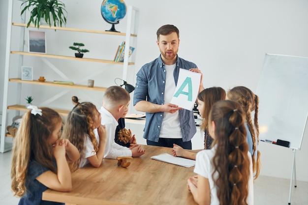 Aprenda uma nova carta Um grupo de alunos em sala de aula na escola com professor