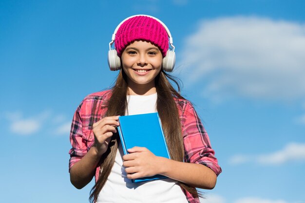 Aprende el idioma de manera diferente Niño feliz usa auriculares en el cielo azul Libro de audio Habilidades de comprensión auditiva y lectura Escuela de idiomas extranjeros Nueva tecnología Enseñanza privada Rompe todas las barreras del idioma