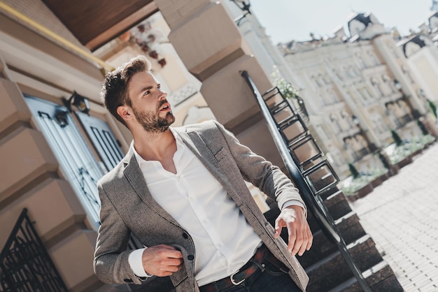 Foto aprende a soltarte, esa es la clave de la felicidad. hombre serio de pelo castaño parado al aire libre.