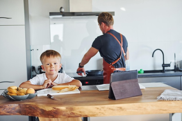 Aprendendo a cozinhar pai e filho estão dentro de casa juntos