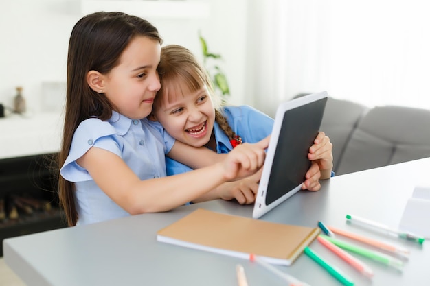 Aprendendo em casa, o conceito de criança de escola em casa. As crianças pequenas estudam a aprendizagem online em casa com um laptop. Quarentena e conceito de distanciamento social.