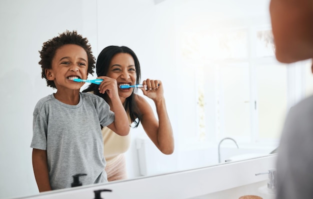 Foto aprendendo mãe e filho escovando os dentes higiene dental e bem-estar em casa banheiro e vínculo família mãe ou mãe com filho do sexo masculino ou menino com saúde bucal, limpeza da boca ou sorriso