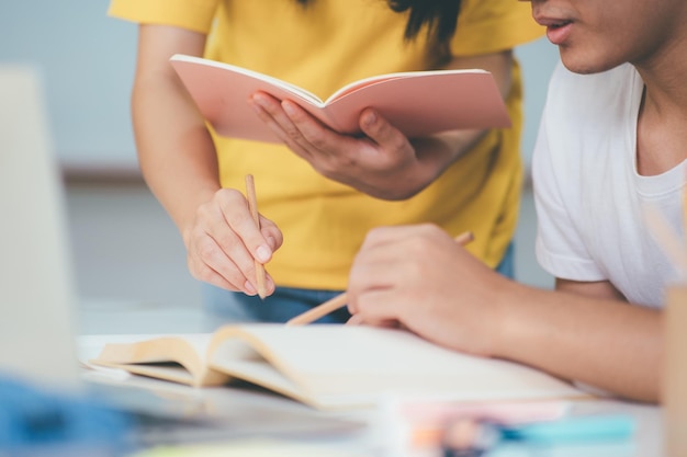 Aprendendo o conceito de educação e escola jovem mulher e homem estudando para um teste ou exame livros de tutor com amigos o campus de jovens estudantes ajuda o amigo a se atualizar e aprender