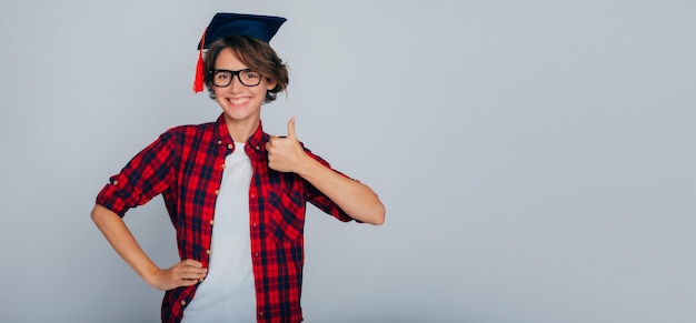 Foto aprender es genial pancarta publicitaria de un graduado lindo y feliz con gafas y una gorra de graduación de maestría muestra un dedo hacia arriba estudio universitario educación clases universitarias graduación de conocimiento