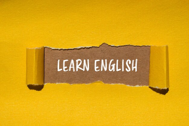 Aprender inglés mensaje escrito en papel amarillo rasgado con fondo marrón Símbolo conceptual de aprender inglés Copiar espacio