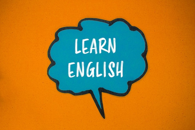 Aprender inglés mensaje escrito en papel azul burbuja de habla con fondo naranja símbolo conceptual aprender inglés copiar espacio