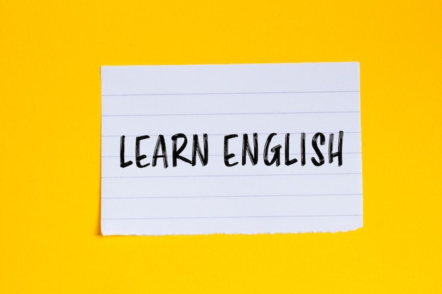 Aprender inglés mensaje escrito en un pedazo de papel blanco rasgado con fondo amarillo Símbolo conceptual de aprender inglés Copiar espacio