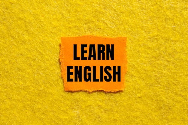 Aprender inglés mensaje escrito en un pedazo de papel naranja rasgado con fondo amarillo Símbolo conceptual de aprender inglés Copiar espacio