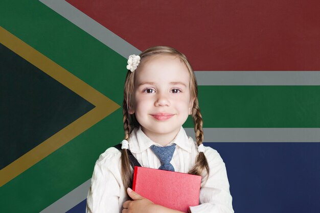 Foto aprender inglés niña inteligente en el fondo de la bandera de sudáfrica