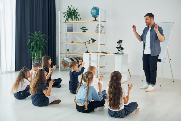 Aprender lenguaje gestual Grupo de niños estudiantes en clase en la escuela con el maestro