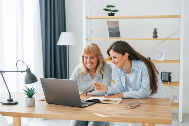 Aprender a usar tecnologías modernas Teléfono inteligente y computadora portátil Madre e hija están juntas en casa