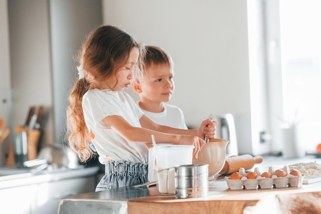 Aprendiendo a cocinar Niño y niña preparando galletas navideñas en la cocina