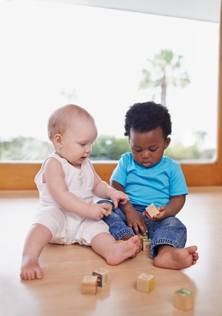 Aprendiendo y creciendo juntos Una foto de dos adorables bebés jugando con bloques de construcción