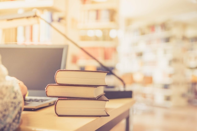 Aprendiendo para los exámenes Estudiante rubia en la biblioteca universitaria pila de libros