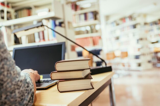 Foto aprendiendo para los exámenes estudiante rubia en la biblioteca universitaria pila de libros