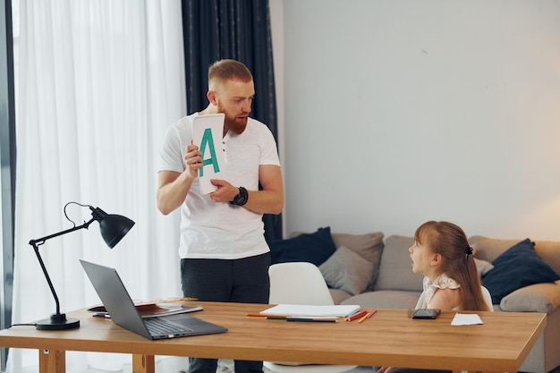 Aprendiendo letras Padre con su pequeña hija está en casa juntos