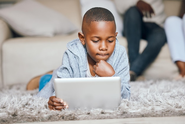 Aprendiendo nuevas cosas. Foto de un niño pequeño usando una tableta digital en casa.