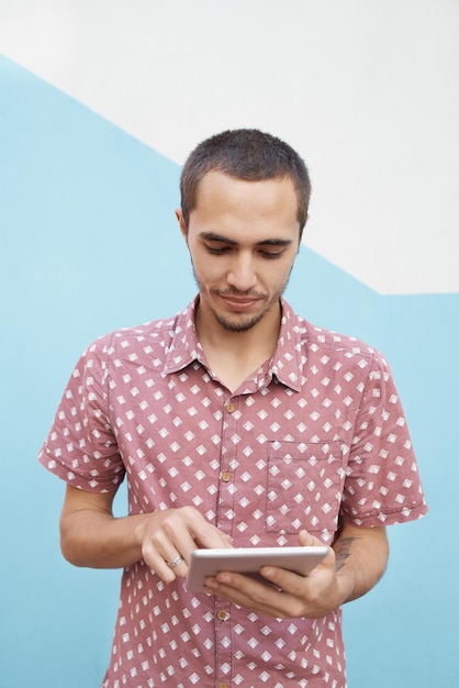 Aprendiendo con solo tocar un botón Captura de un joven estudiante enfocado afuera y trabajando en su tableta antes de la clase