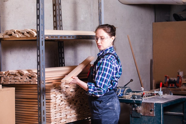 Aprendiz de sexo femenino que comprueba el tablón de madera en el taller de carpintería