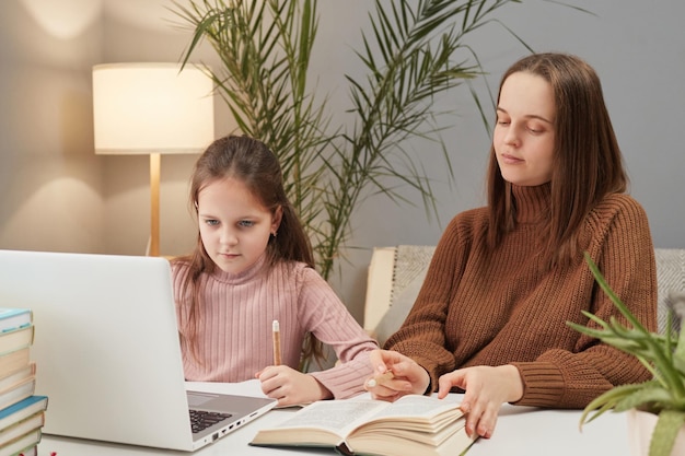 Foto aprendizagem baseada em computador para crianças educação virtual para crianças aprendizado à distância para estudantes menina encantadora com professor usando laptop enquanto está sentada à mesa em casa